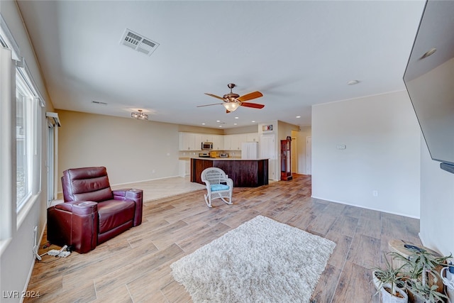 living room with light hardwood / wood-style floors and ceiling fan