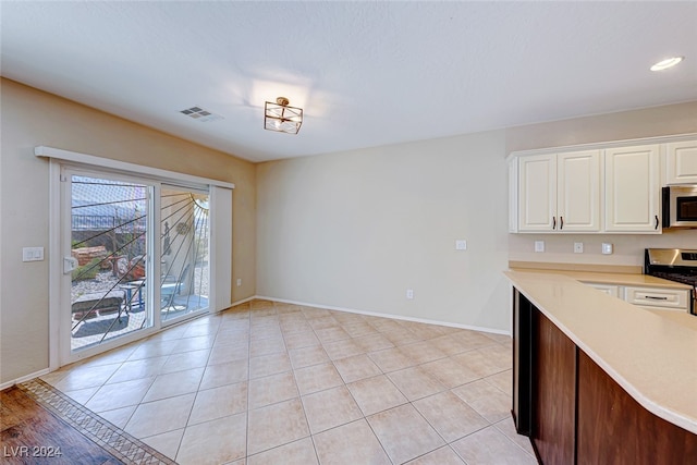 kitchen with white cabinetry, light tile patterned floors, and stainless steel appliances