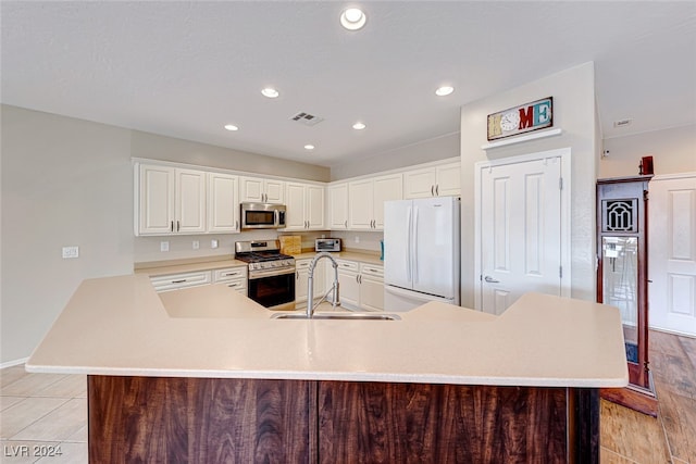 kitchen featuring white cabinets, appliances with stainless steel finishes, sink, and light hardwood / wood-style flooring