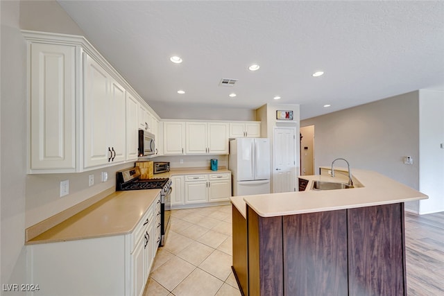 kitchen with stainless steel appliances, white cabinetry, a center island with sink, and sink