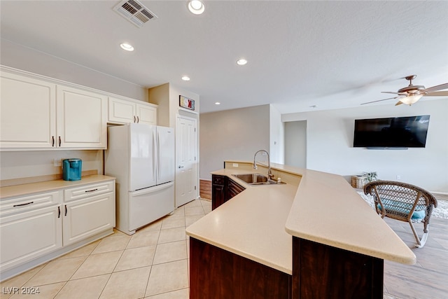 kitchen featuring ceiling fan, sink, a center island with sink, white cabinetry, and white fridge