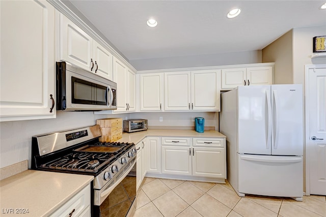 kitchen with light tile patterned floors, stainless steel appliances, and white cabinets