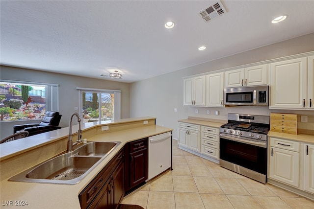 kitchen featuring appliances with stainless steel finishes, sink, light tile patterned floors, and white cabinets