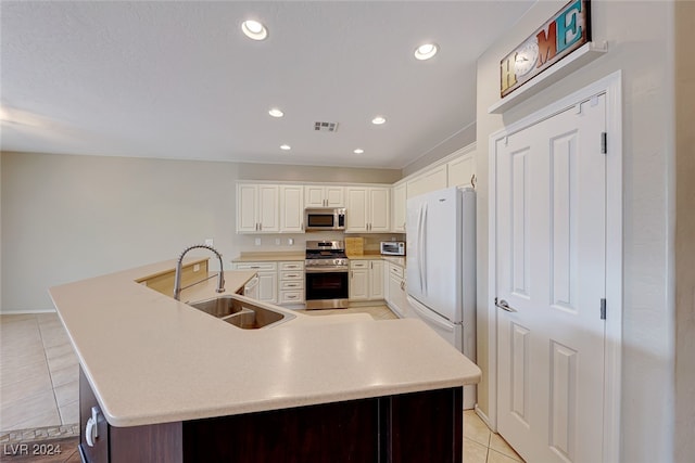 kitchen with light tile patterned flooring, sink, an island with sink, white cabinetry, and stainless steel appliances