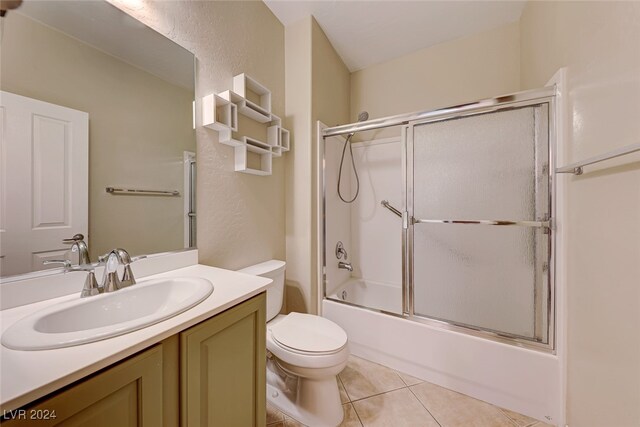 full bathroom with tile patterned floors, bath / shower combo with glass door, vanity, and toilet