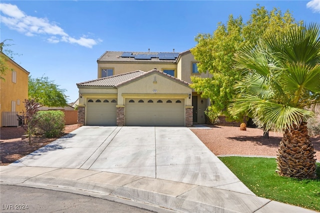 mediterranean / spanish-style home with central AC unit, solar panels, and a garage