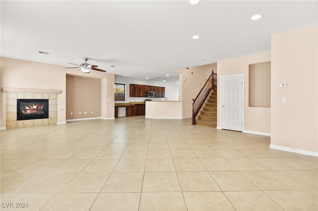 unfurnished living room with ceiling fan, light tile patterned flooring, and a fireplace