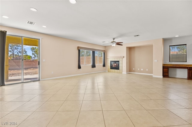 unfurnished living room with light tile patterned flooring, a tiled fireplace, and ceiling fan