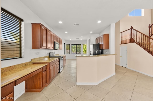 kitchen featuring light stone countertops, sink, stainless steel appliances, and light tile patterned floors