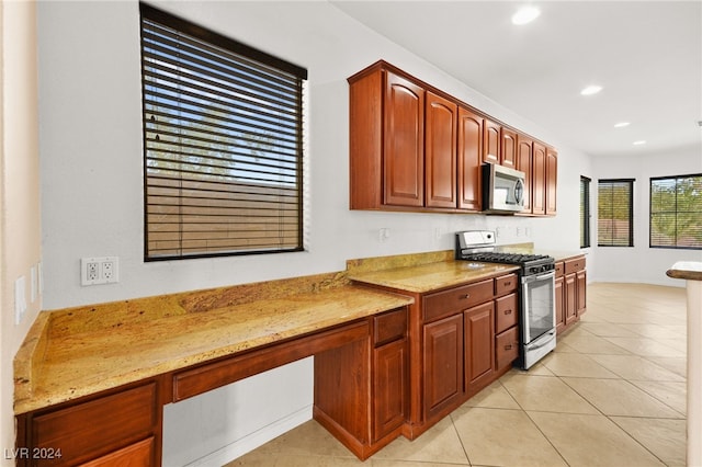 kitchen with appliances with stainless steel finishes, light tile patterned flooring, and light stone countertops