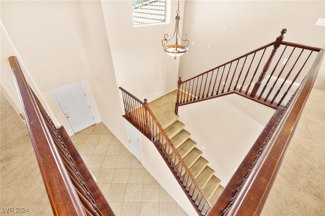 stairs featuring a high ceiling, a chandelier, and tile patterned floors