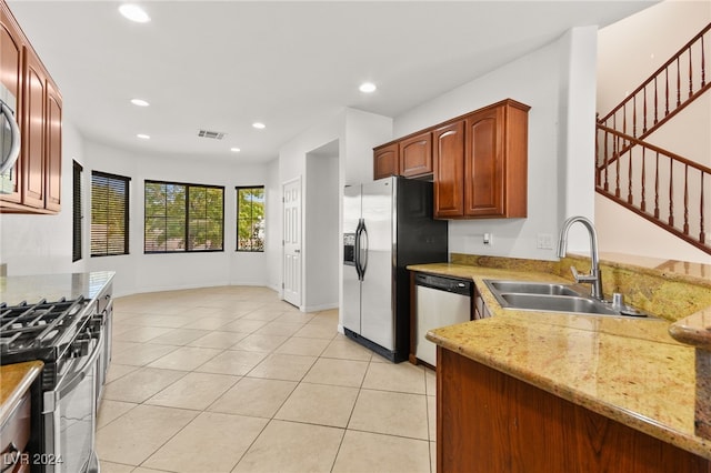 kitchen featuring light stone countertops, appliances with stainless steel finishes, light tile patterned floors, and sink