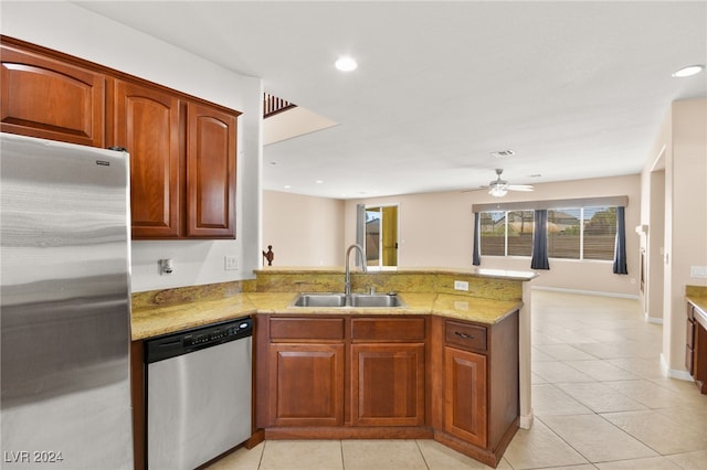 kitchen with light stone counters, sink, kitchen peninsula, appliances with stainless steel finishes, and ceiling fan