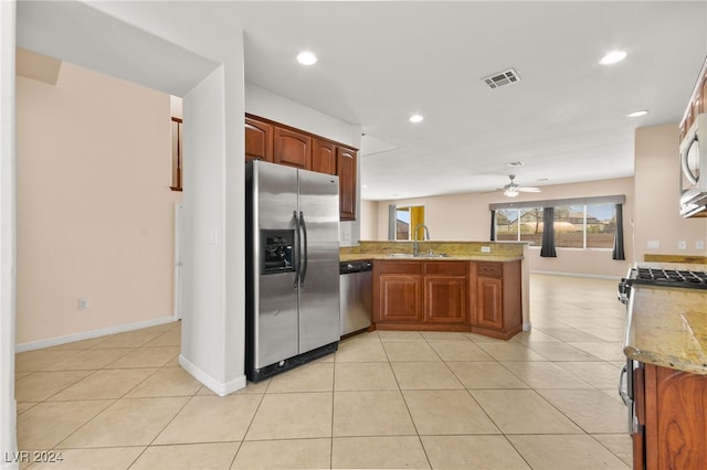 kitchen featuring sink, kitchen peninsula, stainless steel appliances, light stone countertops, and ceiling fan