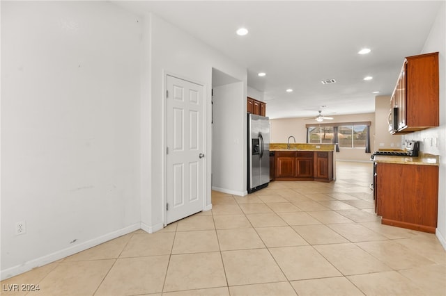 kitchen featuring kitchen peninsula, light tile patterned floors, stainless steel appliances, ceiling fan, and sink