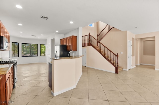 kitchen featuring light tile patterned floors, sink, appliances with stainless steel finishes, and kitchen peninsula