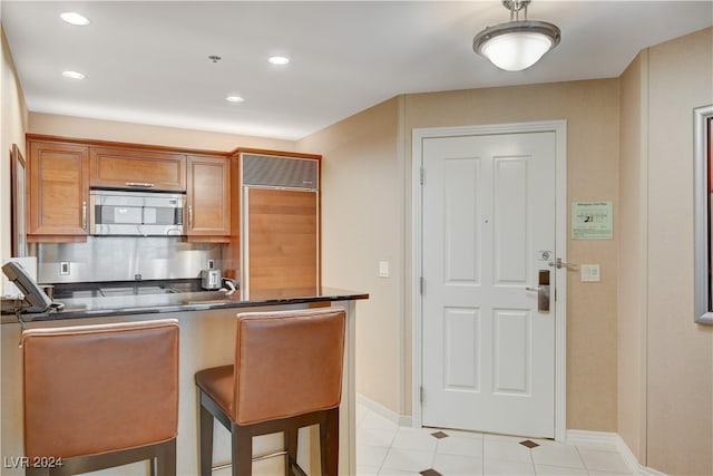 kitchen featuring a kitchen bar, light tile patterned flooring, and built in refrigerator