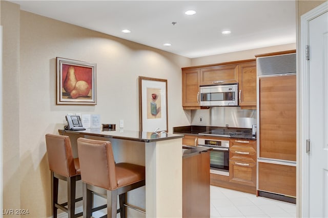 kitchen with appliances with stainless steel finishes, kitchen peninsula, and a kitchen breakfast bar