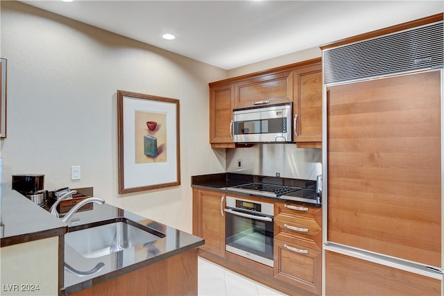 kitchen with appliances with stainless steel finishes, light tile patterned flooring, and sink