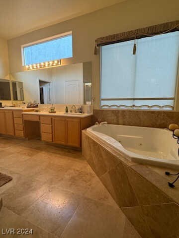 bathroom featuring tiled tub, vanity, and tile patterned flooring