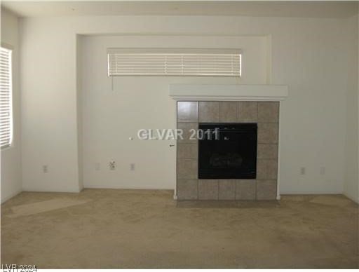 unfurnished living room featuring a tiled fireplace and carpet