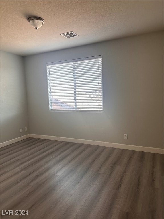 empty room featuring a textured ceiling and dark hardwood / wood-style flooring