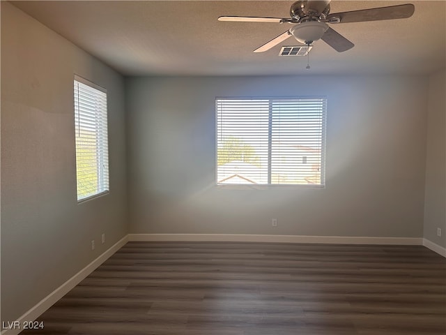 empty room with a textured ceiling, dark hardwood / wood-style flooring, ceiling fan, and plenty of natural light