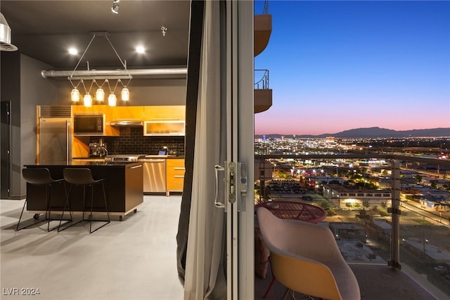 balcony at dusk featuring exterior bar