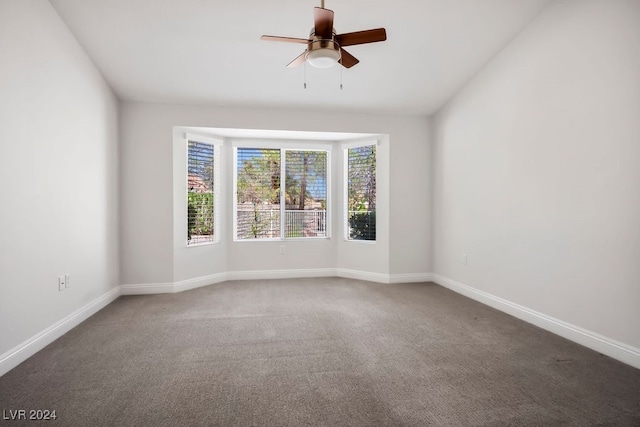 spare room with ceiling fan, dark carpet, and lofted ceiling