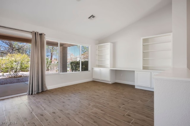 unfurnished room with dark hardwood / wood-style floors, built in desk, and lofted ceiling