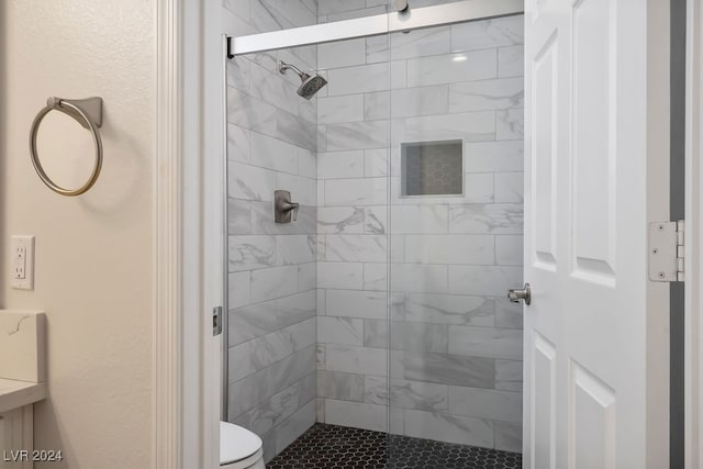 bathroom featuring toilet and a shower with shower door