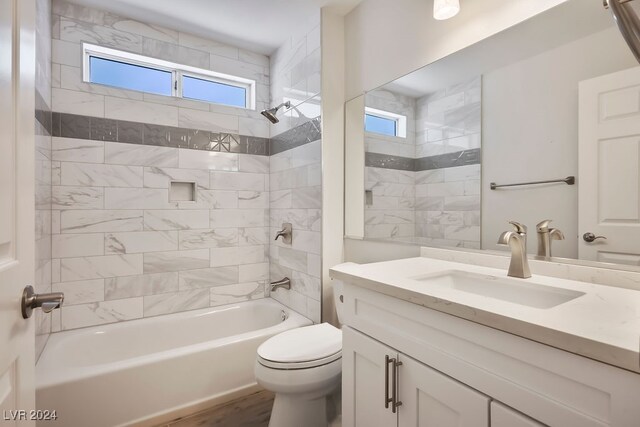 full bathroom featuring vanity, tiled shower / bath combo, toilet, and a healthy amount of sunlight