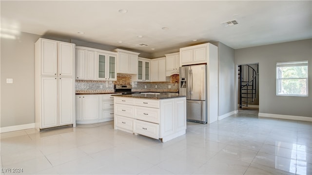 kitchen featuring tasteful backsplash, stainless steel appliances, white cabinetry, light tile patterned floors, and a center island