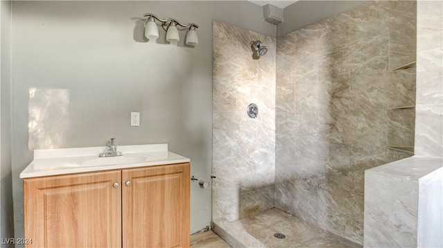 bathroom with tiled shower and vanity