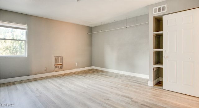 unfurnished bedroom with heating unit and light wood-type flooring