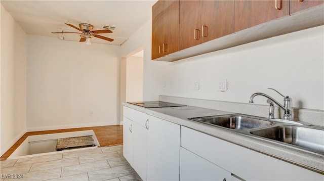 kitchen with black electric stovetop, white cabinetry, sink, light hardwood / wood-style floors, and ceiling fan