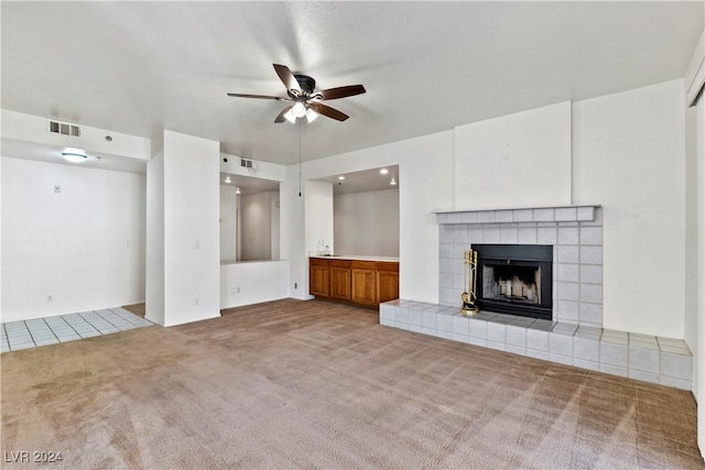 unfurnished living room featuring light carpet, ceiling fan, and a tile fireplace