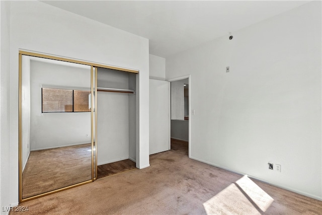 unfurnished bedroom featuring light colored carpet and a closet