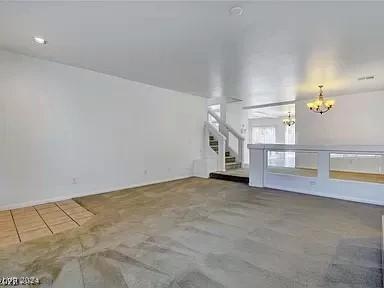 unfurnished living room featuring a chandelier