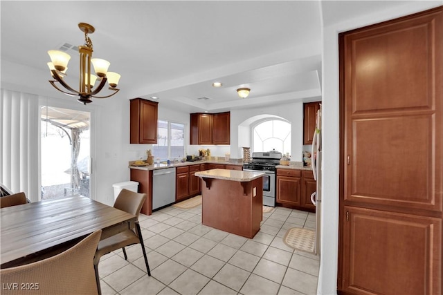 kitchen featuring decorative light fixtures, light tile patterned floors, a kitchen island, a notable chandelier, and stainless steel appliances