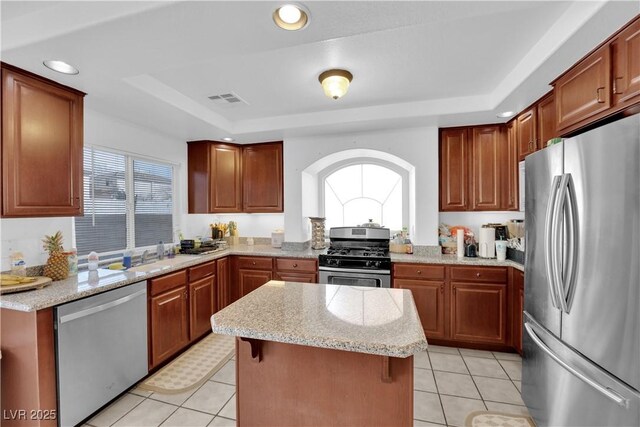 kitchen with visible vents, a center island, light stone counters, stainless steel appliances, and a raised ceiling