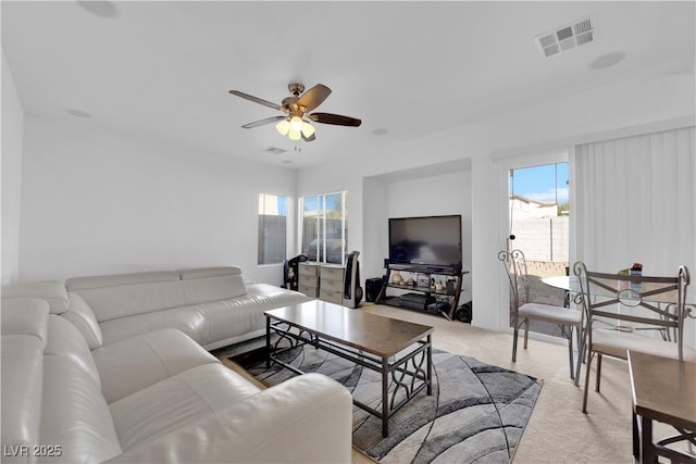 living area featuring visible vents, a ceiling fan, and carpet