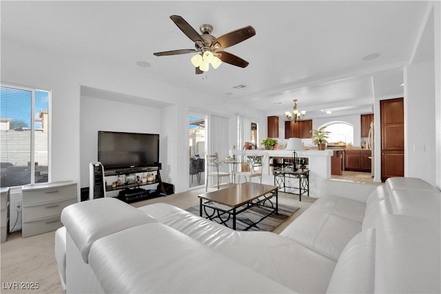 living room with light carpet, plenty of natural light, ceiling fan with notable chandelier, and visible vents