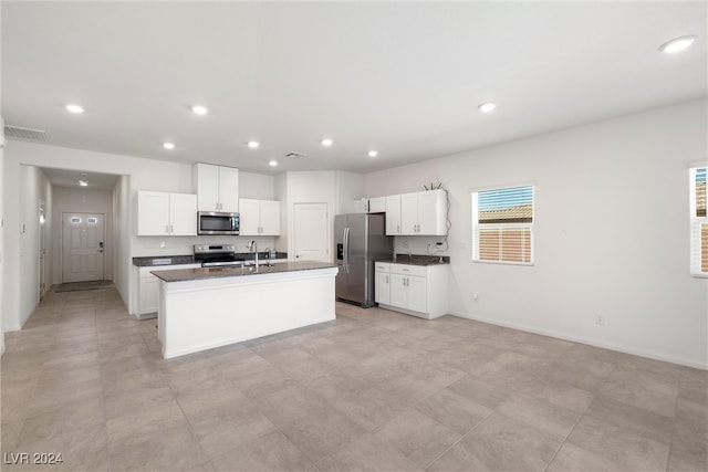 kitchen featuring white cabinets, stainless steel appliances, sink, and an island with sink