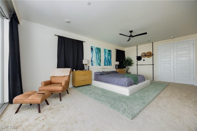 carpeted bedroom with ceiling fan and a closet