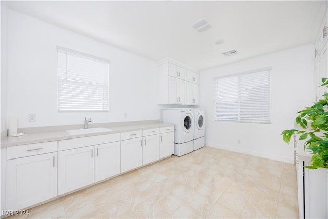 washroom with cabinets, washer and clothes dryer, and sink