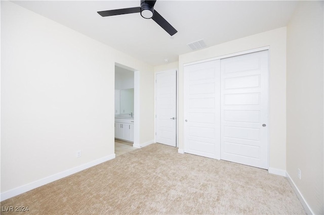 unfurnished bedroom featuring connected bathroom, ceiling fan, a closet, and light colored carpet