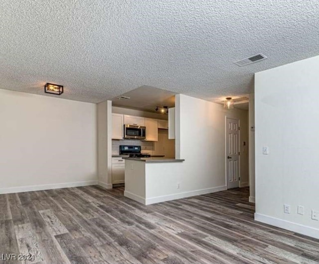 kitchen with black range oven, wood-type flooring, a textured ceiling, and white cabinetry