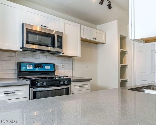 kitchen with tasteful backsplash, light stone countertops, stainless steel appliances, and white cabinets