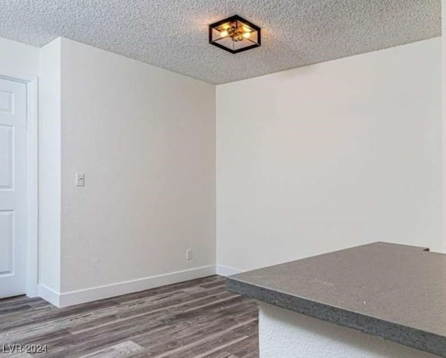 spare room featuring a textured ceiling and dark hardwood / wood-style floors